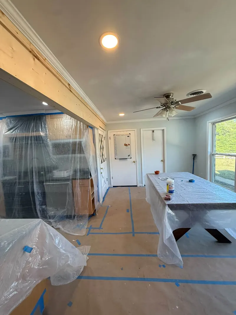 Painted room with recessed lights, ceiling fan and wood trim, floors covered with paper and tape