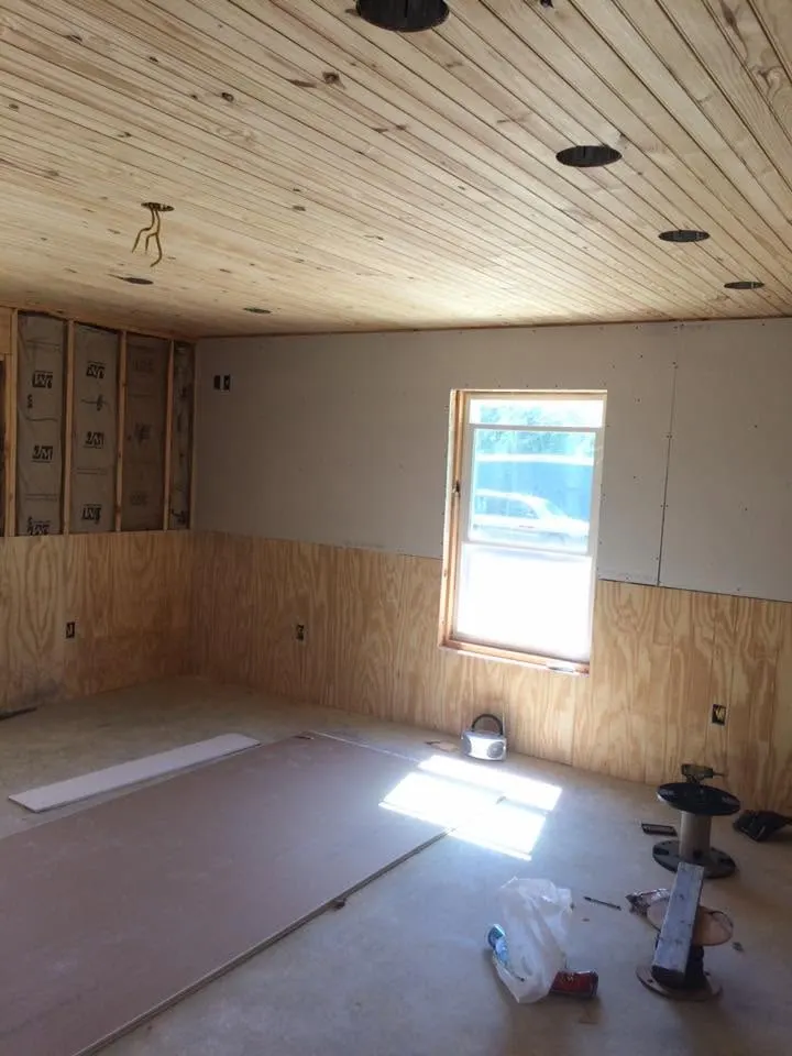 Interior with tongue-and-groove wood ceiling, plywood walls and a window, during construction