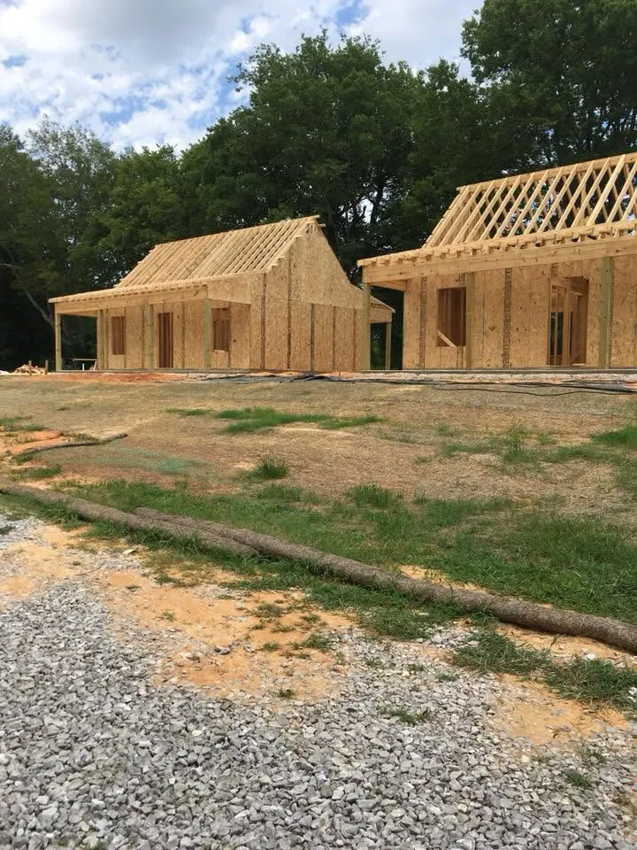 Two framed cottages with roof trusses and sheathing in progress