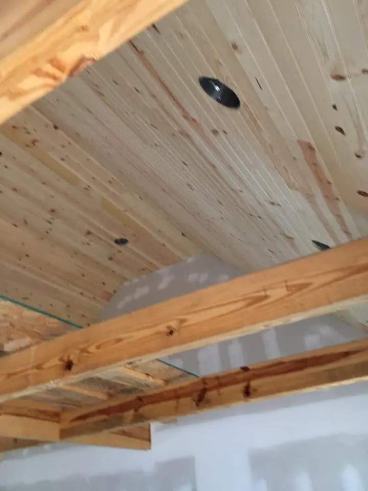 Tongue-and-groove wood ceiling with exposed beams and recessed light openings