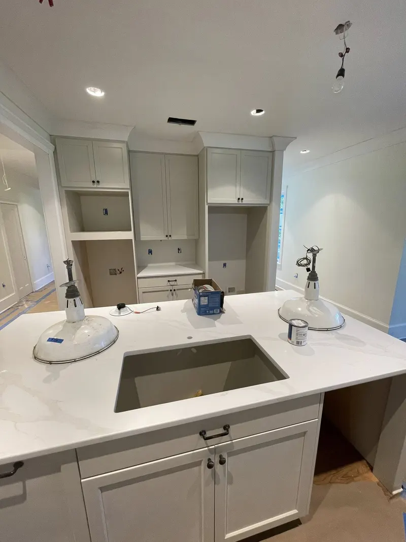 Kitchen island with undermount sink and white cabinets, with built-in shelving behind