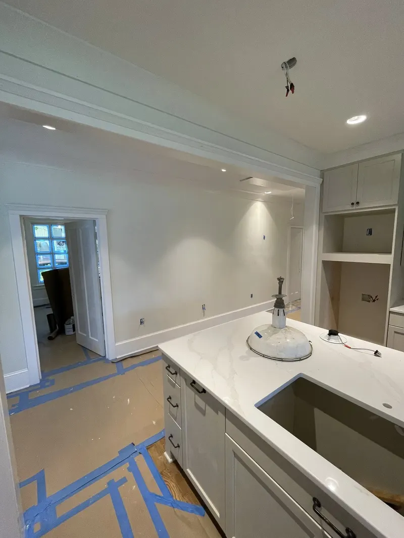 White kitchen counter with sink and built-in cabinets beside a doorway