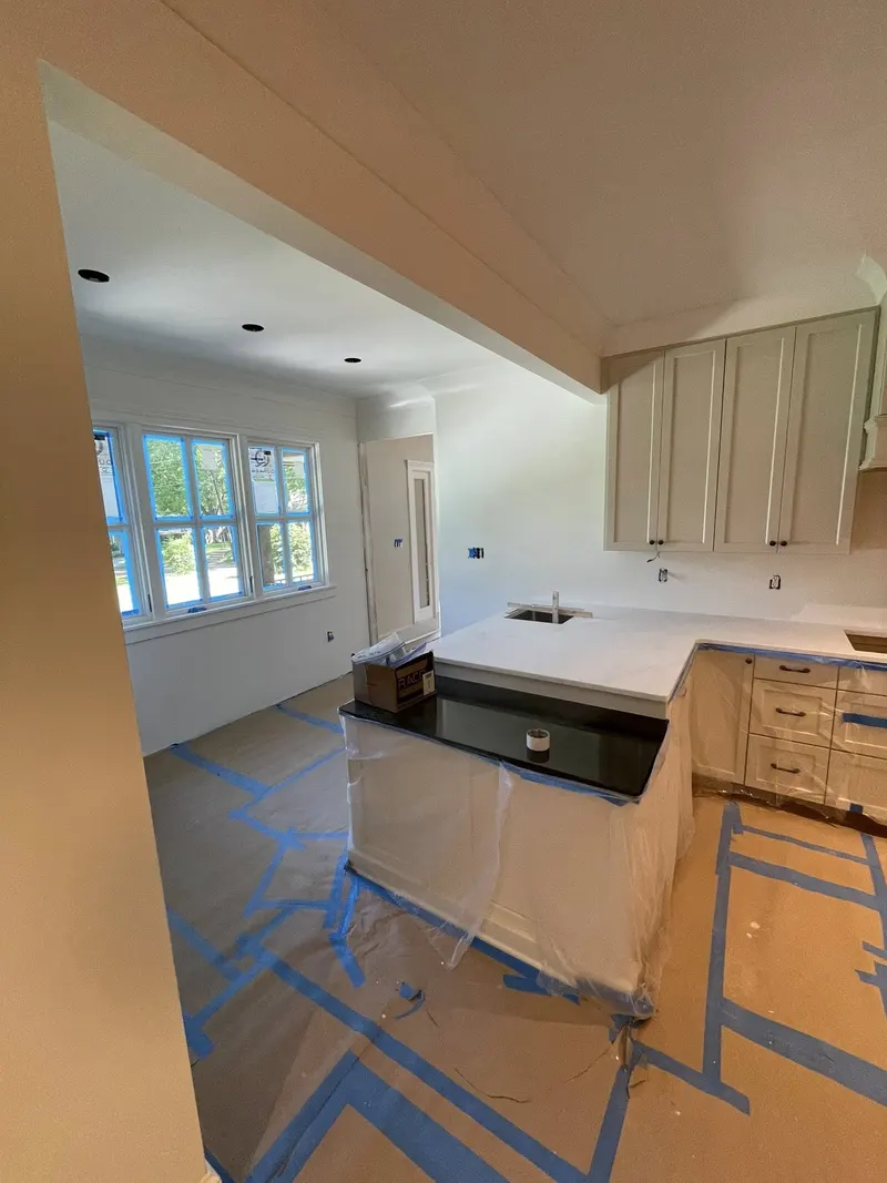 Kitchen with white cabinets and a dark-topped island seen through a cased opening