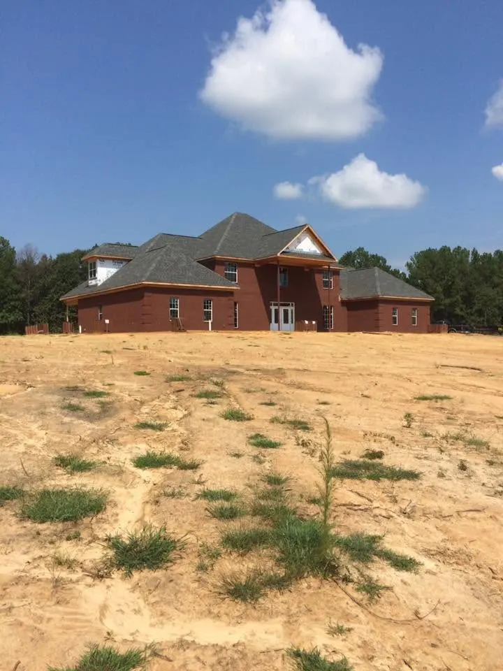 Two-story brick house seen across a newly cleared lot