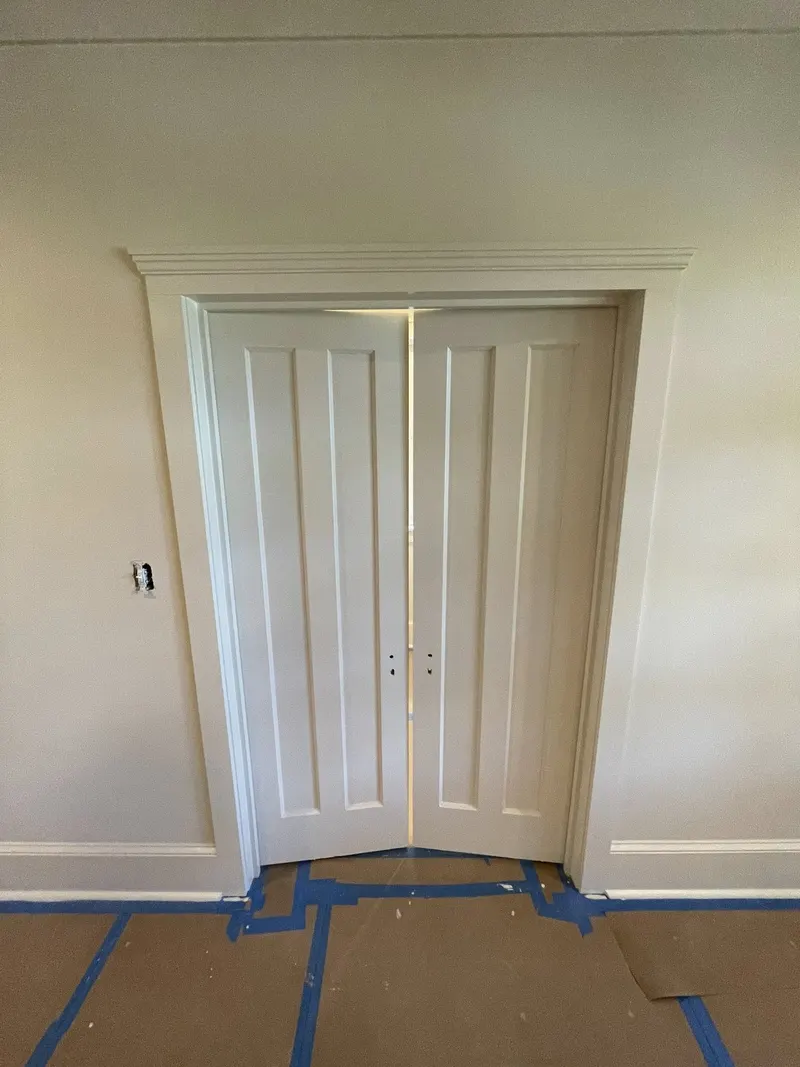 Paneled double doors with painted casing and baseboards